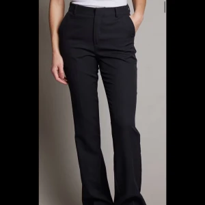 Svarta kostymbyxor med normal passform - Snygga svarta kostymbyxor med klassisk rak passform och hög midja. Perfekta till både vardagliga och mer uppklädda outfits.