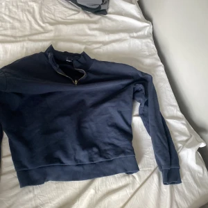 Mörkblå half zip sweatshirt Divided - Nu säljer jag denna Mörkblå sweatshirt från Divided med half zip-dragkedja i halsen. Tröjan har lång ärm, ribbade muddar och en relaxed passform. Perfekt för en chill och stilren look. Tillverkad i mjuk bomullsmix som är skön att bära. Kom med frågor är alltid aktiv