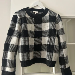 Svartvit stickad tröja - Säljer en stickad tröja från H&M i storlek XS med svartvitt rutigt mönster. Passar mig som är S/M. Tröjan har rund halsringning, långa ärmar och ribbade muddar. 