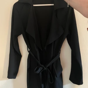 Svart kappa - Stilren svart tunn kappa med långa ärmar och snyggt knytbälte i midjan. 