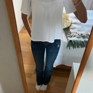 Vit blus med broderi från Zara - Superfin vit blus från Zara med broderade detaljer upptill och korta ärmar. Blusen har en lös passform, rund halsringning och knapp i nacken. Perfekt till jeans eller kjol för en fräsch look. Tillverkad i mjuk bomull som känns skön mot huden. Storlek 164 men passar xs. Köp gärna via postnord