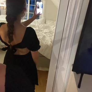 Svart klänning med puffärmar - Säljer en superfin svart klänning.  Klänningen har volang i kjolen, öppen rygg sol man knyter med en rosett. Man kan ha ärmarna både på axlarna men också off shoulder! Aldrig använd. 