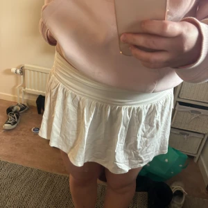 Vit kortkjol från Nelly - Säljer en vit kortkjol från Nelly med bred resår i midjan. Materialet känns mjukt och bekvämt mot huden. Helt oanvänd, endast testad.