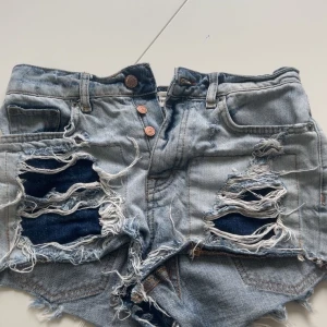 Ljusblå slitna jeansshorts från Perfect Jeans - Riktigt snygga ljusblå jeansshorts med kraftiga slitningar och fransar. Knappar framtill och klassisk femficksmodell. Perfekta för sommaren när du vill ha en cool och avslappnad look.