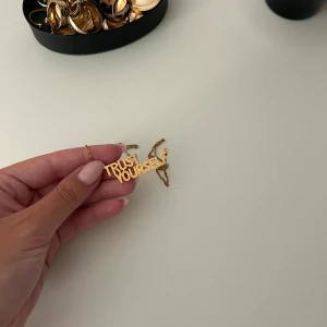 IOAKU halsband - Säljer ett trendigt halsband i guld med texten 'Trust Yourself' som hänge. Nyskick från IOAKU