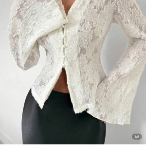 Vit blus med knappar och struktur - Säljer en vit blus med spets tyg och dekorativa knappar framtill. Blusen har långärmade, lätt utsvängda ärmar och en unik krage som ger en cool look. Perfekt att styla till både kjol och byxor. Säljer pågrund av att den är för stor för mig, inte använd och köpt på Shein 💞