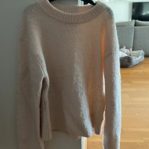 Ljusbeige stickad tröja från H&M - Mysig ljusbeige stickad tröja från H&M med rund halsringning och långa ärmar. Perfekt för lager-på-lager och enkel att matcha med olika outfits.