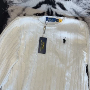 Vit kabelstickad tröja från Polo Ralph Lauren - Säljer en klassisk vit kabelstickad tröja från Polo Ralph Lauren med broderad logga på bröstet. (Storlek är M men den är lite mindre passform i armarna) passar perfekt S-M FLER BILDER FINNS ATT VISSA IFALL DU ÄR INTRESSERAD 