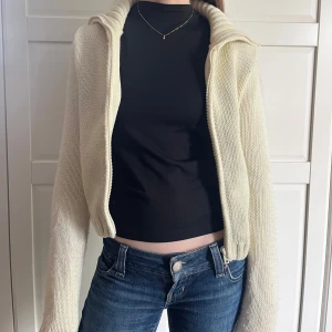 Stickad vit hoodie med dragkedja - Mysig stickad hoodie i vit färg med dragkedja framtill. Jackan har lång ärm, ribbade muddar och nederkant samt en luva. Passar perfekt nu till sommaren🌄