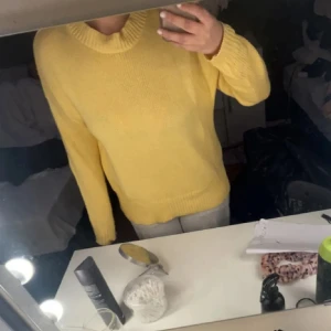 Gul stickad tröja med rund hals - Säljer en söt gul stickad tröja med rund halsringning. Tröjan har lång ärm och en klassisk, enkel design som passar perfekt till jeans eller kjol. Supermjuk och skön att ha på sig! Nytt skick 