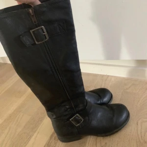 Svarta höga boots med detaljerat spänne 💫 - Snygga svarta boots i skinn material. Dragkedja på sidan och coola spänndetaljer upptill och vid ankeln. Köpta secondhand, se skicka på bilderna ❤️Storlek 37 (passar även mig som vanligtvis har 38.5) Kom gärna med prisförslag 🎀