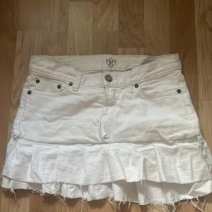 Vit jeanskjol med volanger, stl 28 - Vit kort jeanskjol med volangkant och råa, fransiga kanter. Köpt på vinted men passade inte, lite offwhite på vissa ställen. Skulle säga storlek xs-s💕💕