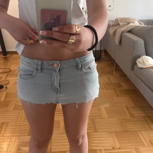 Ljusblå jeans minikjol med rå kant - kort ljusblå jeanskjol med rå, fransig kant och slitna detaljer. Klassisk femficksmodell med dragkedja och knapp framtill. Bakfickorna har en cool zigzag-söm. Perfekt för dig som gillar en edgy och trendig stil. Ett par gamla jeans som jag klippt själv. På etiketten står de 12-13y men jag som 14 år och är 158 kan ha dem.