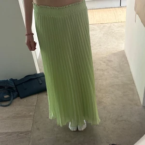 Ljusgrön plisserad långkjol - Säljer en ljusgrön plisserad långkjol med resår i midjan. Kjolen har ett luftigt och flowy tyg som ger en snygg siluett. Den är i nyskick utan prislapp!