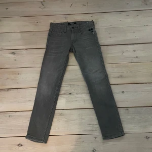 Grå jeansbyxor från Replay - Snygga grå jeansbyxor från Replay med klassisk femficksdesign och raka ben. Byxorna har diskreta sömmar på bakfickorna och Replay-logga vid fickan fram. Perfekta för en stilren och avslappnad look.