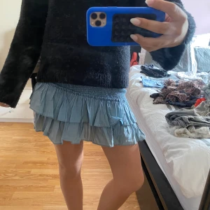 Ljusblå volangkjol med resår - Supersöt ljusblå kortkjol med volanger och smock i midjan. Kjolen är perfekt för varmare dagar.