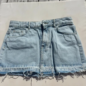 Ljusblå jeanskjol från Pull and Bear - Ljusblå jeanskjol från Pull and Bear. Fransiga kanter och klassiska fickor både fram och bak. Endast använd fåtal gånger.