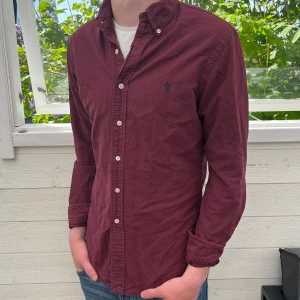 Vinröd Ralph lauren skjorta - Säljer jätte fin vinröd Ralph lauren skjorta, inga synliga tecken på användning och jätte fint skick, modellen är slimfit och den postas inom 48h, bara att skriva vid funderingar👍