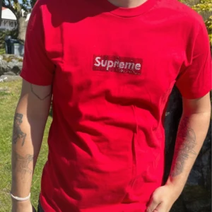 Supreme x Swarovski Box Logo Tee 25 year special - Jubileumssläpp (25th Anniversary 2019) äkta Swarovski-kristaller. Supreme t-shirt i rött Klassisk passform och korta ärmar. Tillverkad i 100% bomull för en skön känsla. Perfekt statement-plagg för streetwear.