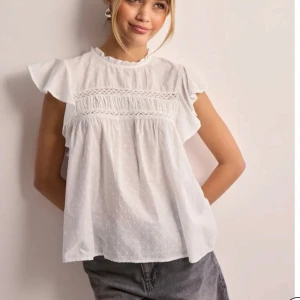 Vit blus med spetsdetaljer - Säljer en söt vit blus med spetsdetaljer och korta volangärmar. Blusen är knappt använd💕för bättre bilder är det bara att höra av sig💕