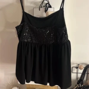 Svart paljett topp 🥹💘 - Snygg svart topp från Gina Tricot med glittriga paljetter upptill och smala axelband. Perfekt för en festlig kväll! ✨Använd en gång 💘