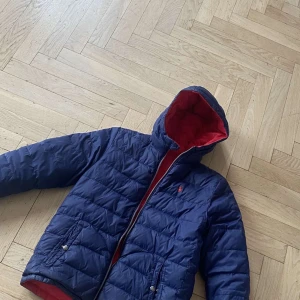 Blå och röd dunjacka från Polo Ralph Lauren - Säljer en snygg blå dunjacka som går att vände ut och in så den blir röd från Polo Ralph Lauren. Jackan har en huva och dragkedja framtill. Jackan är i ett bra skick utan defekter. Jackans nypris ligger på ca 3000kr mitt pris 699 vid en snabb och smidig affär.Skulle sig att den passar dig som är 150-164cm, storleken är xl barn. Perfekt nu för våren men funkar även utmärkt på hösten! Hör av er vid frågor💫