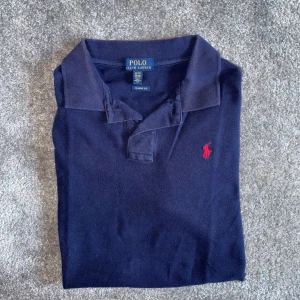 pikétröja från Ralph Lauren - Säljer en klassisk mörkblå pikétröja från Ralph Lauren med röd logga på bröstet.  Passar perfekt för en skön outfit! Passar storlek S-M. Nypris 1099 vårat pris 299. Kom dm för frågor!