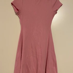 Rosa ribbad klänning från Sister - Säljer en söt rosa ribbad klänning från Sister. Den har en enkel design med korta ärmar och en bekväm passform!
