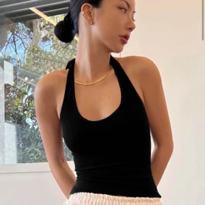 Svart halterneck linne - Snyggt svart halterneck linne med knytning i nacken. Perfekt för en stilren och enkel look. Passar bra till både jeans och kjol.