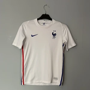 Fotbollströja  - Säljer en vit fotbollströja från Nike. Tröjan är i storlek 160-155 passar även mindre. Skick 6/10 skada på sida 4 som ni kan se. Bara att skriva för eventuella frågor. 