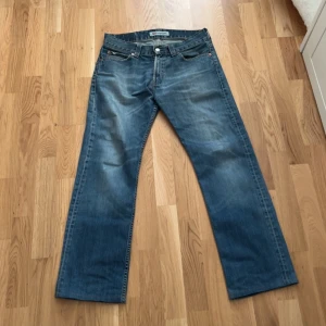 Levi’s 506 standard - Säljer ett par klassiska blå Levi's 506 jeans. De har en rak passform och är tillverkade i slitstarkt denim. Byxorna har fem fickor och stängs med dragkedja och knapp. Perfekta för en avslappnad stil. Det står L34 men jeansen är en mindre modell så passar de som L32. Perfekta för någon som är 173-175cm
