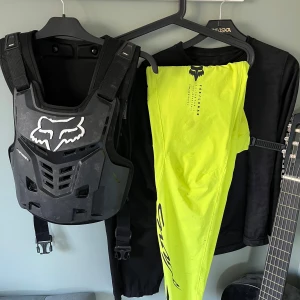 Svart skyddsväst från Fox - Säljer en svart skyddsväst från Fox med justerbara remmar och ventilerande design. Perfekt för cykling eller motocross. Västen har en robust konstruktion och en stilren logga på framsidan.