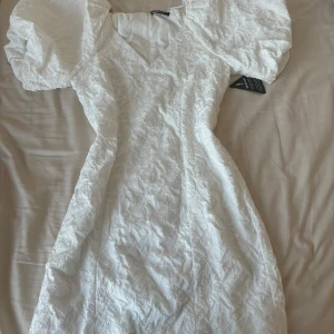 Studentklänning  - Säljer en vit klänning med puffiga kortärmar och v-ringning. Klänningen sitter så fint runt midjan och brösten!!! Nyskick aldrig använt😍😍😍 jättepopulär och slutsåld överallt säljer då denna inte är i min storlek