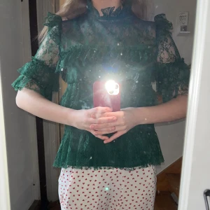 Grön By Malina spetsblus - Säljer en elegant grön spetsblus med volanger och korta ärmar. Inga defekter eller hål och använt 2-3 gånger