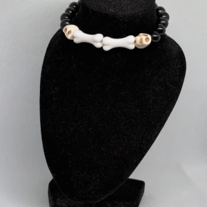 Svart och vitt armband med dödskallar - Unikt armband med svarta pärlor och vita detaljer i form av ben och dödskallar. Perfekt för att ge en edgy touch till din stil.