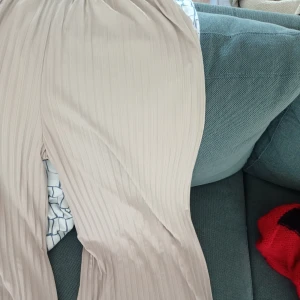 Beige plisserade byxor - Snygga beige plisserade byxor med loose fit och elastisk midja. Perfekta för en avslappnad stil med en touch av elegans. Passar bra till både vardag och speciella tillfällen. Endast använda 2 ggr, köpta i Australien 