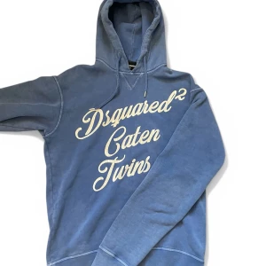 Blå hoodie från Dsquared2 - Säljer en snygg blå hoodie från Dsquared2 med texten 'Caten Twins' i vitt på framsidan. Tröjan har inga defekter! Mitt pris:  699 kr men kan diskuteras! Skriv vid behov av fler bilder eller vid minsta fundering! Nypris: 3500kr!