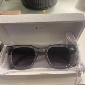 Grå solglasögon från Chimi 04 - Snygga grå solglasögon från Chimi i modellen 04. I nytt skick aldrig använda. Snygga nu till våren/ sommaren för att pigga upp en outfit. Mycket fint skick. 
