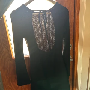 Svart klänning med öppen rygg - Elegant svart klänning med långärmad design och en snygg öppen rygg. Använd få gånger. Storlek S.