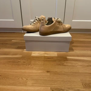 Beige sneakers från Maison Margiela - Snygga beige sneakers från Maison Margiela. Helt nya och har snörat dem som man ser på första bilden till skilland mot sista. Otroligt bra pris med tanke på skicket! Det finns en fet dustbag med. Säljer för att jag använder andra skor. Fråga gärna om det är något😊