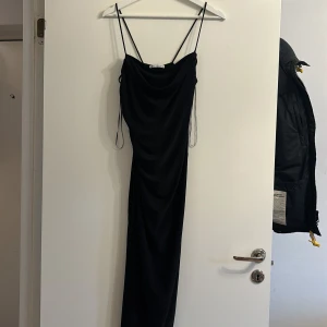 Svart långklänning från Zara - Elegant svart långklänning från Zara med smala axelband och draperad design. Perfekt för en stilren look. Klänningen har en enkel och tidlös stil som passar många tillfällen.