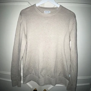 Beige tröja från Jack & Jones - Säljer en stilren beige tröja från Jack & Jones. Tröjan har en klassisk rund hals och långa ärmar. Perfekt för en avslappnad look. Passar bra till både jeans och chinos.