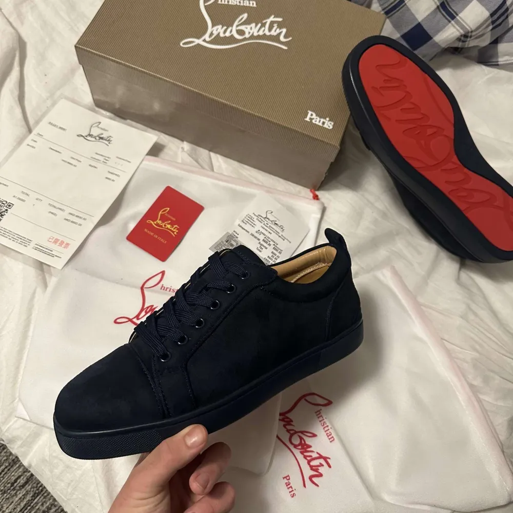 Snygga mörkblåa sneakers från Christian Louboutin med den ikoniska röda sulan. Skorna har en stilren design med snörning och är tillverkade i skinn. Perfekta för dig som vill ha en lyxig touch i vardagen.. Kengät.