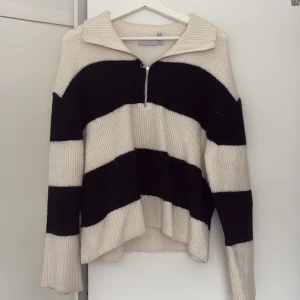 Randig stickad tröja från Weekday - Säljer en snygg randig tröja från Weekday i svart och beige. Tröjan är stickad med en dragkedja framtill och har långa ärmar. Perfekt för en stilren och bekväm look.
