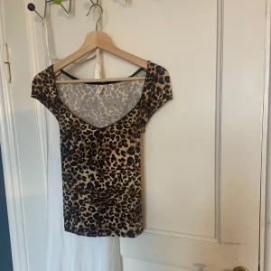 Leopardmönstrad topp från Nelly - Säljer en snygg leopardmönstrad topp från Nelly. Toppen har en tight passform och korta ärmar, perfekt för en trendig look. Första bilden är lånad. Sorlek M men skulle säga passar S.💕🐆