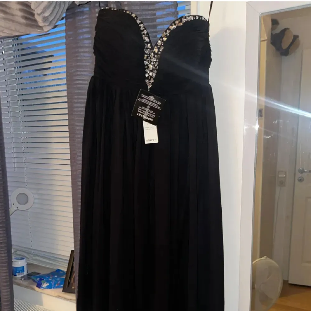 Ny oanvänd elegant svart axelbandslös klänning från Nelly Eve med silvriga diamant stenar längs den hjärtformade urringningen. Storlek XS men passar även S. Perfekt till bal eller andra fina tillfällen. . Mekot.