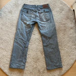 Blå jeansbyxor från Levi's - Snygga blå jeansbyxor från Levi's med design. Byxorna har en rak passform och två coola fickor💕storleken är ”20 regular 30x30” men skulle uppskatta den till en 36 😊