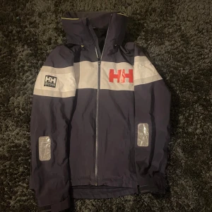 Helly Hansen Seglarjacka - Seglarjacka från Helly Hansen i toppskick! Nypris runt 3800kr. Storlek S passar runt 180 och luvan går att stoppa in i kragen ifall man vill det. Herrmodell men passar både tjej & kille!