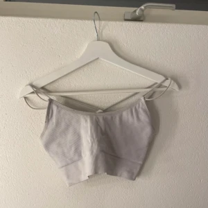 Vit ribbad croppad linnetopp - Säljer en stilren vit ribbad croppad linnetopp med smala axelband. Perfekt för varma sommardagar eller som ett till träningen. Enkel och snygg design som passar till det mesta. Ska flytta snart så vill gärna bli av med allt så fort som möjligt (pris kan diskuteras)💕