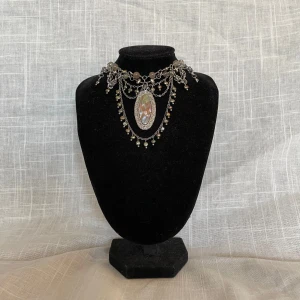 Silverfärgat halsband med hänge - Ett silver halsband för alla mina silver girlies.  Detta halsband är gjort med rostfritt stål. Hänget är köpt secondhand och är därför i en okänd metall.  Jag har experimenterat med ”chainmail” mönster av olika slag och implementerat det i designen. 